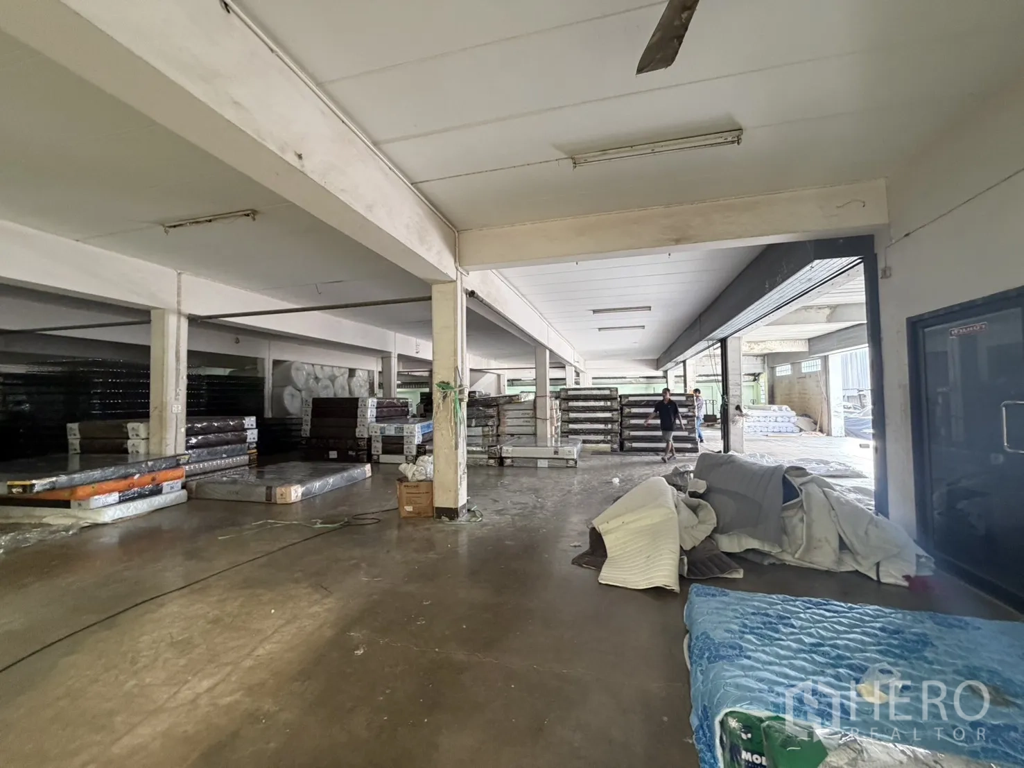 Factory for rent or sale in Bang Bon, Bangkok - Warehouse zone with open roller shutters and stacked products.
