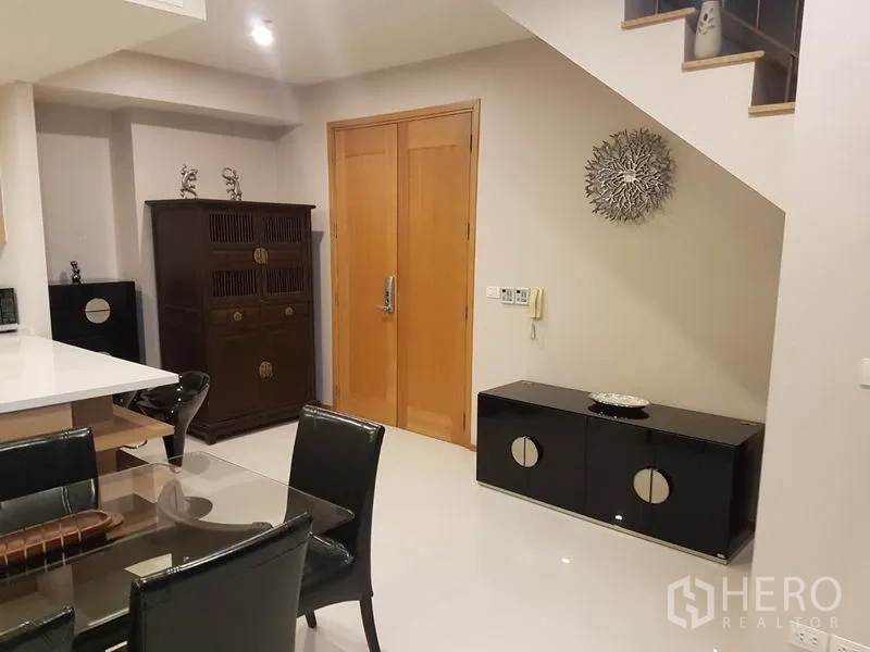 Condominium for rent or sale in Khlong Toei, Bangkok - Entrance hall with wooden door, storage cabinets and stairs in a modern condo.