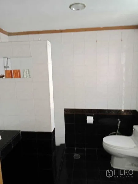 Townhouse for rent in Khlong Toei, Bangkok - Bathroom with black-and-white tiles and walk-in shower zone.