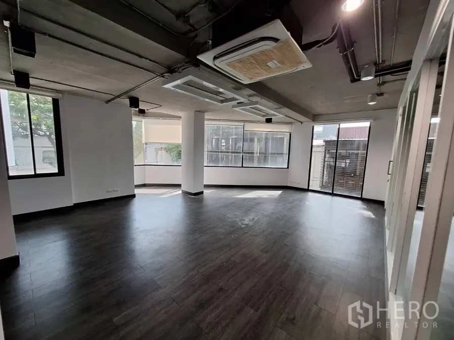 Office Space for rent - Spacious open-plan office with large windows, dark flooring and cassette air-conditioning.