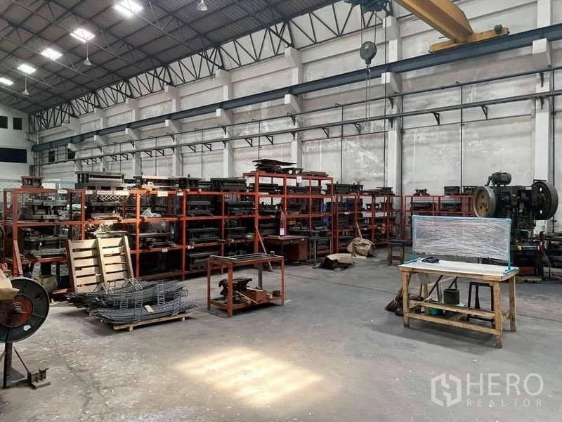 Factory for rent in Phra Samut Chedi, Samut Prakan - Storage racks and worktables beneath a gantry crane hook in a well‑lit factory.
