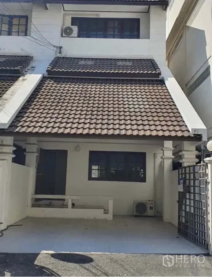Townhouse for rent in Watthana, Bangkok - Two-storey townhouse exterior with tiled roof and gated carport in Watthana, Bangkok.