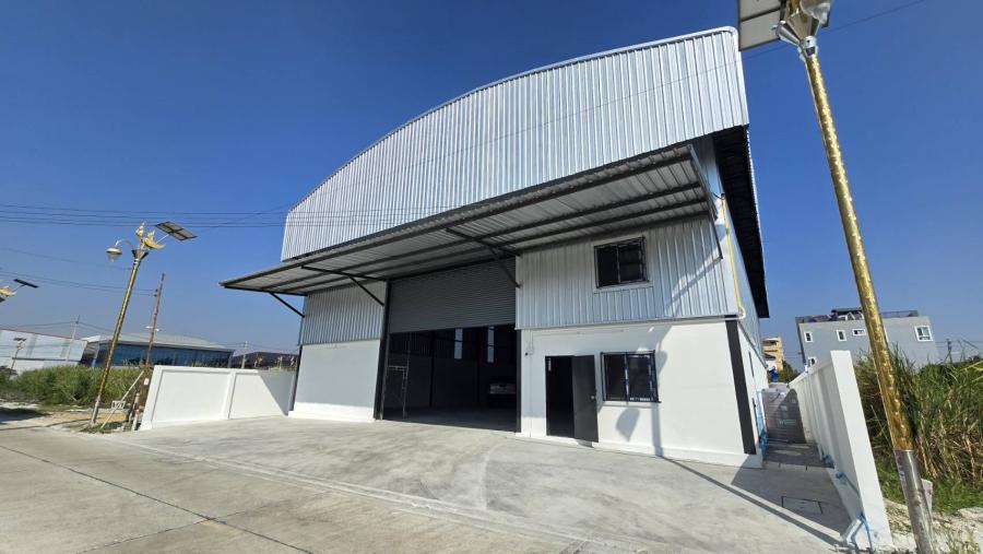 Warehouse for rent in Bang Phli, Samut Prakan - Modern steel-clad warehouse exterior with wide roller shutter and concrete forecourt.