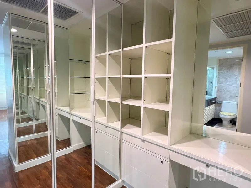 Condominium for rent or sale in Khlong Toei, Bangkok - Walk-in closet with mirrored doors, built-in shelves and dressing counter.