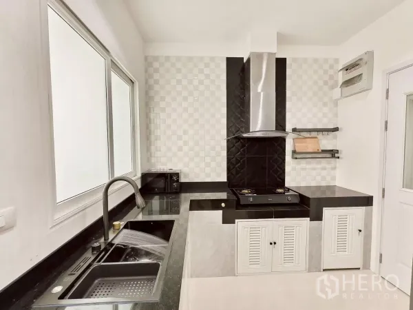 Detached House for rent in Khlong Luang, Pathum Thani - Modern Thai kitchen with black granite counters, gas hob and stainless hood