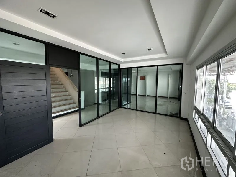 Factory for rent or sale in Bang Bua Thong, Nonthaburi - Glass-partitioned office suite with stair access and wraparound windows.