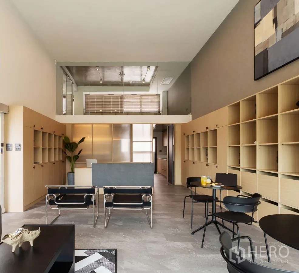 Home Office for rent or sale in Bang Khen, Bangkok - Double-height reception area with mezzanine, built-in shelving, and modern seating.