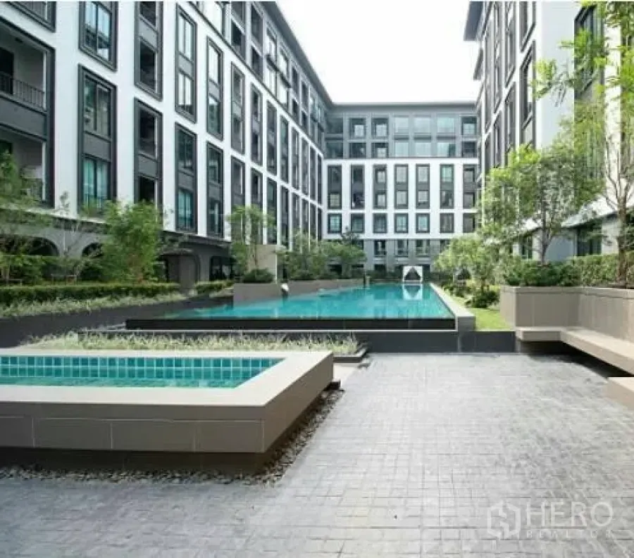 Condominium for rent in Pathum Wan, Bangkok - Modern low-rise condominium courtyard with a long swimming pool, greenery and seating areas.
