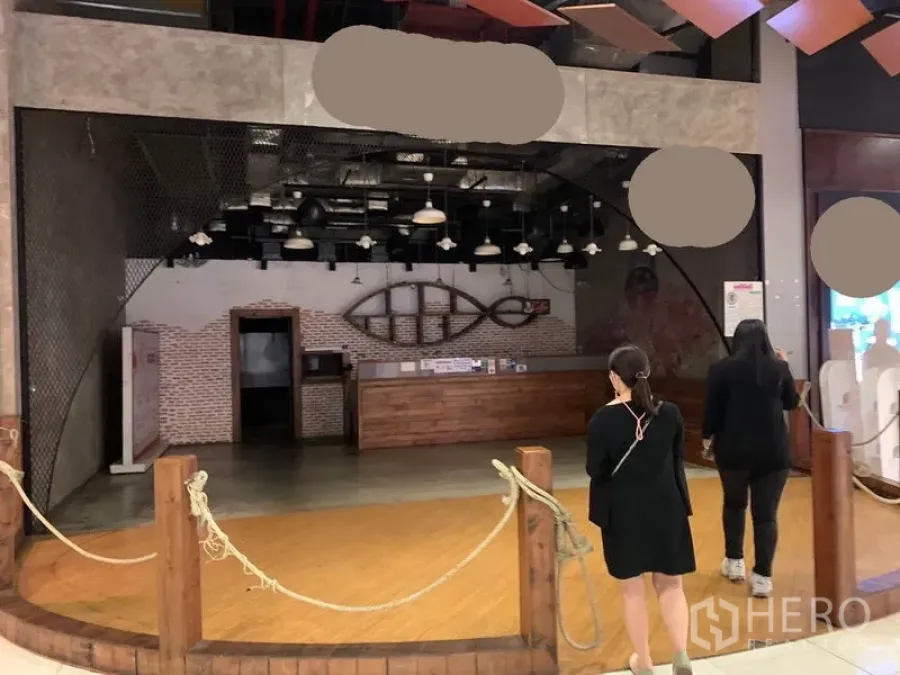 Retail Space for rent in Khlong Toei, Bangkok - Open-front retail unit in a mall with wooden counter, brick feature wall and industrial pendant lighting.