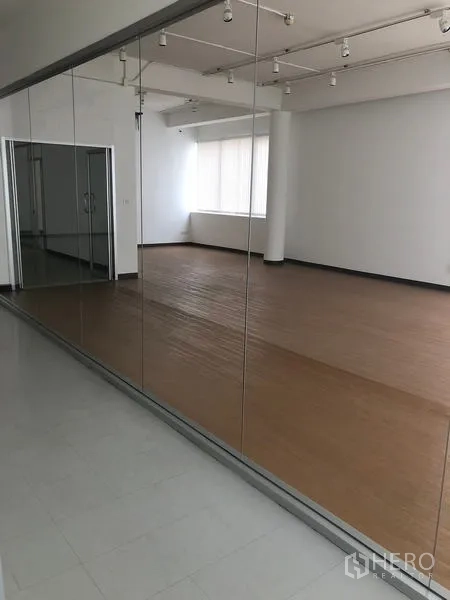 办公空间 出租在Bang Rak, Bangkok - 整面镜面玻璃隔断，映射出带百叶的大型办公空间。
