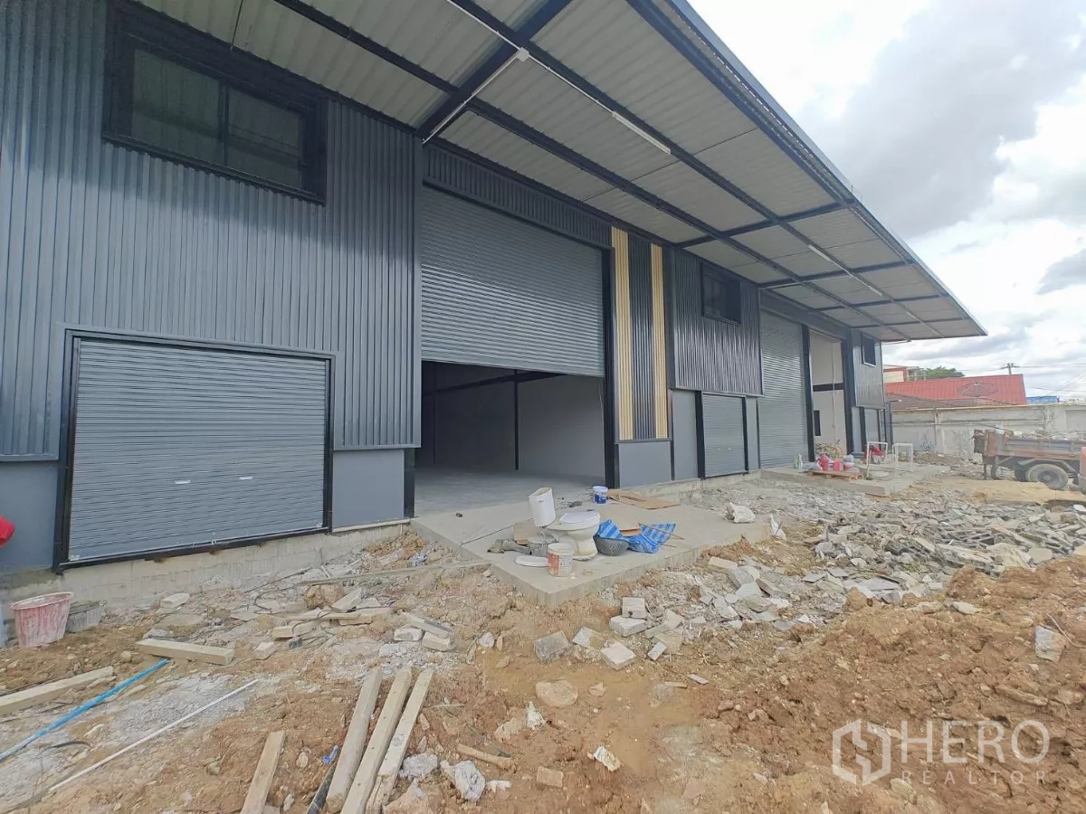 Warehouse for rent in Sam Phran, Nakhon Pathom - Newly built warehouse exterior with multiple roller shutter bays and a covered loading area in Sam Phran.