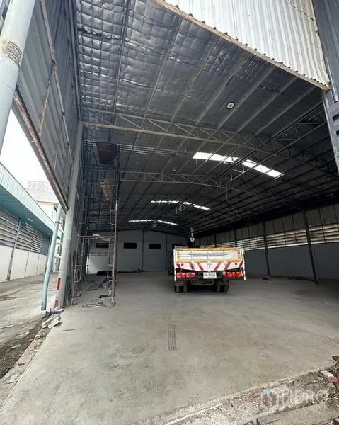 Warehouse for rent in Suan Luang, Bangkok - Spacious high-ceiling warehouse interior with insulated steel roof, skylights and concrete floor, truck parked.