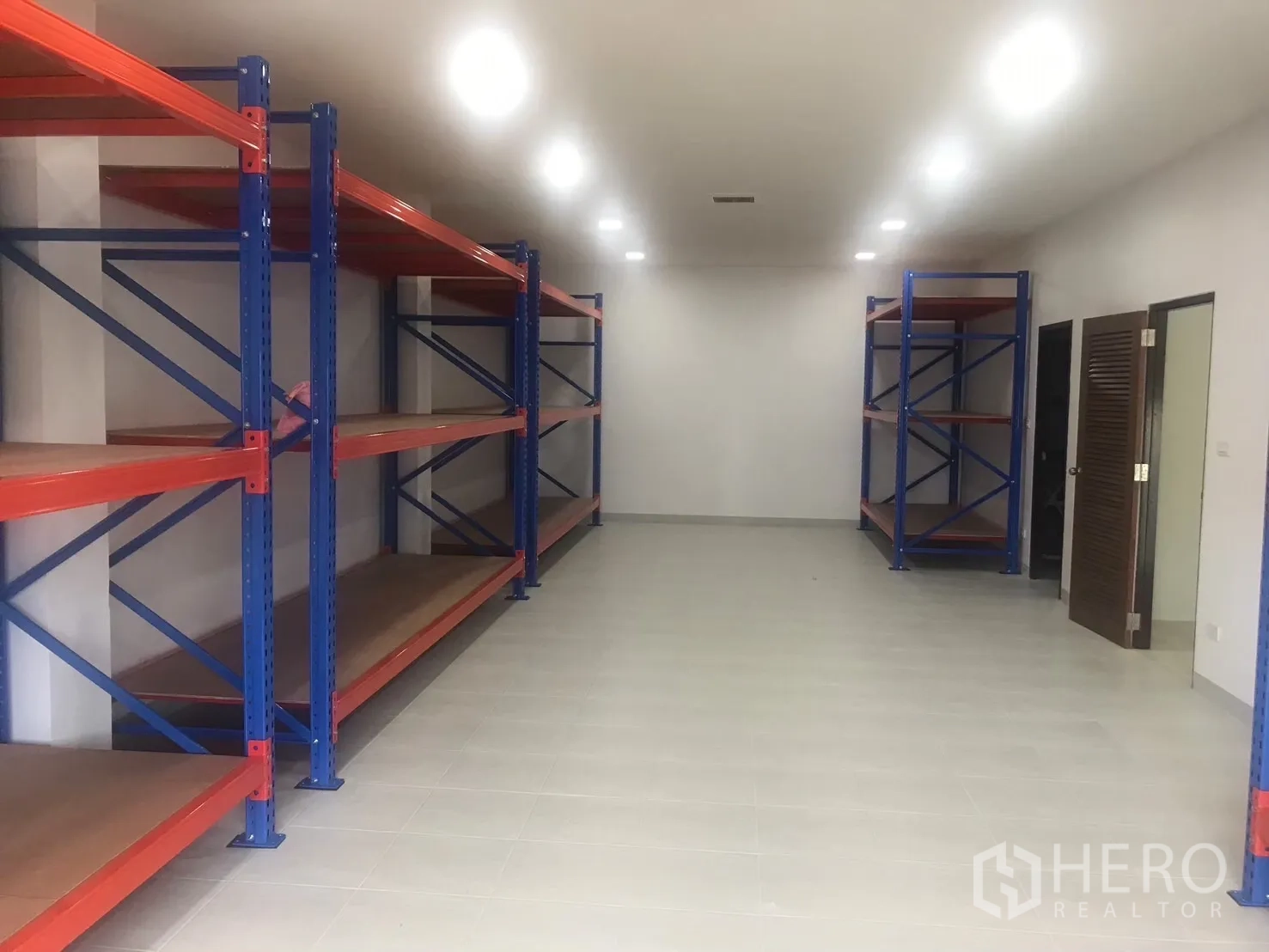 Factory for sale in Krathum Baen, Samut Sakhon - Clean storage room fitted with blue and orange heavy-duty shelving racks.