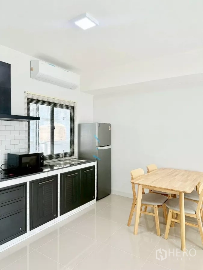 Townhouse for rent in Bang Phli, Samut Prakan - Kitchen with window, stainless sink, fridge and wooden dining table.
