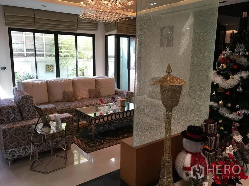 独立式住宅 出租在Khlong Toei, Bangkok - 明亮客厅，花纹沙发、水晶吊灯与玻璃茶几，临近大窗。