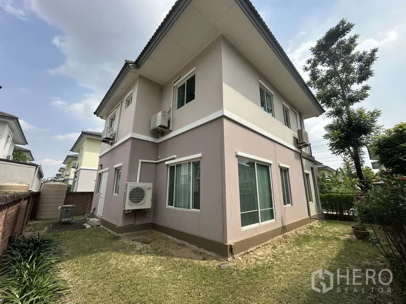 独立式住宅 出售在Sai Mai, Bangkok - 房屋后角，草地、窗户与外挂机。