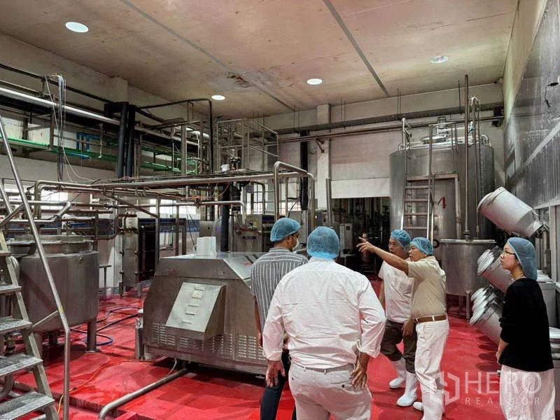 Factory for sale in Samut Prakan - Industrial mixing and pasteurizing equipment set under a high concrete ceiling.