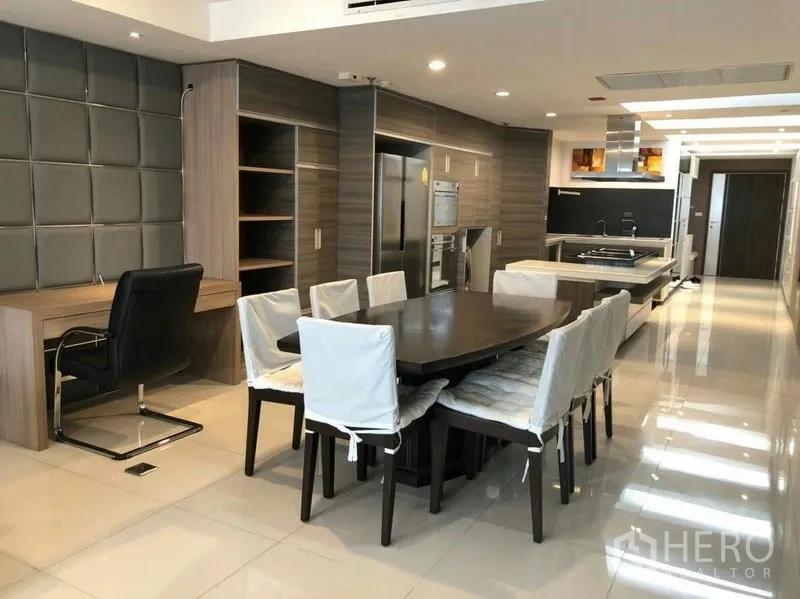 Condominium for rent or sale in Watthana, Bangkok - Open-plan dining area with eight-seat table beside a modern island kitchen and wood cabinetry.