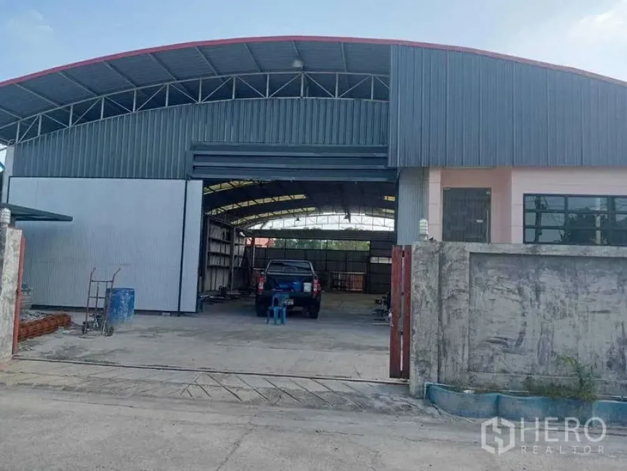 货栈 出租在Lam Luk Ka, Pathum Thani - 仓库正面，拱形钢结构屋顶，宽幅卷帘门与车道