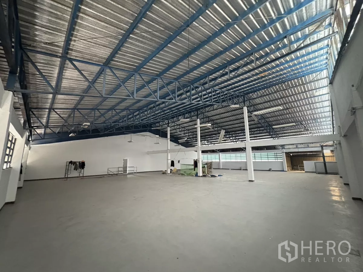 Factory for rent in Khlong Toei, Bangkok - Large production hall with high metal roof, blue trusses and ample natural light.