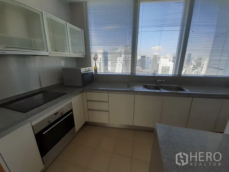 Condominium for rent in Khlong Toei, Bangkok - Enclosed modern kitchen with city skyline view, double sink and ample cabinets.