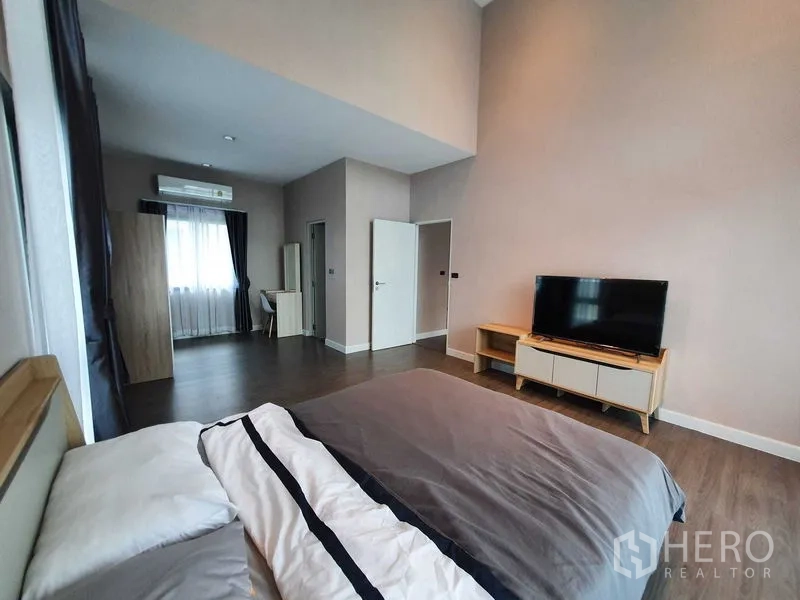 Detached House for rent in Khlong Luang, Pathum Thani - Master suite angle showing bed, TV and adjoining dressing area with air conditioning.