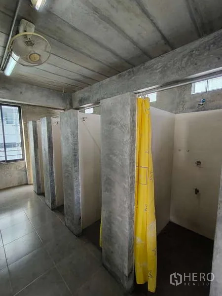 货栈 出租在Huai Khwang, Bangkok - 多间独立淋浴间，带黄色浴帘的水泥隔间。