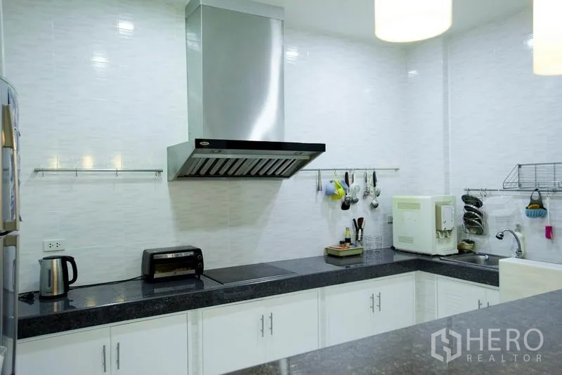 Home Office for rent in Wang Thonglang, Bangkok - U-shaped white kitchen with granite countertop, cooktop and stainless steel hood.