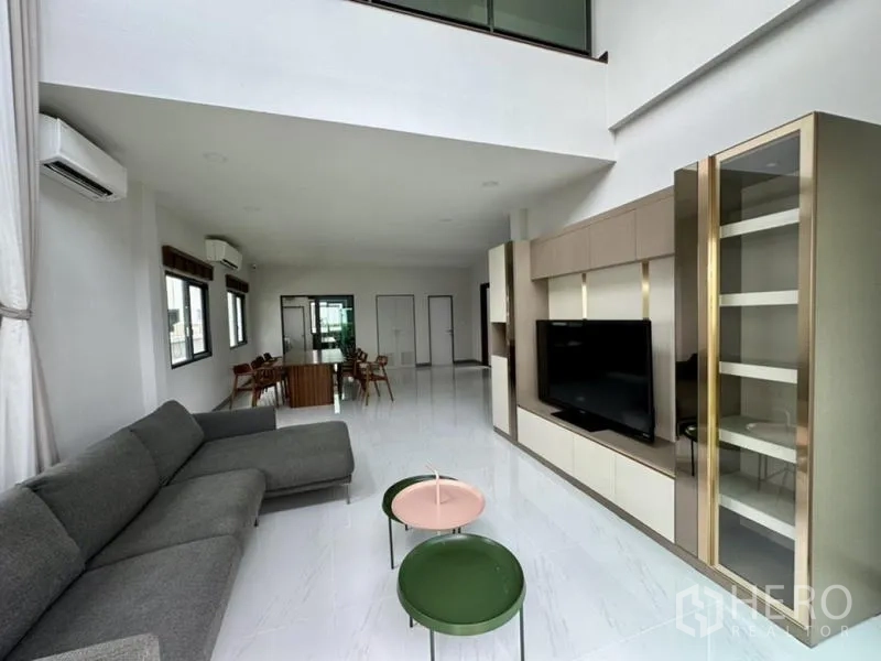 Detached House for rent in Bang Phli, Samut Prakan - Double-height living room with sectional sofa and built-in TV wall unit.