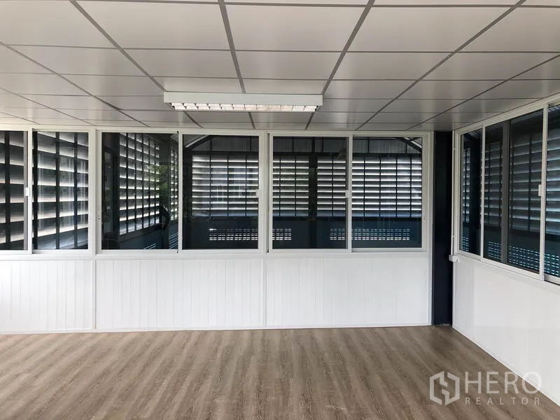 Factory for rent or sale in Bang Bua Thong, Nonthaburi - Upper office room with drop ceiling, wide windows, and wood-look flooring.