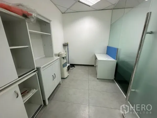 Office Space for rent - Utility room with white storage cabinets and desk behind a frosted glass partition.