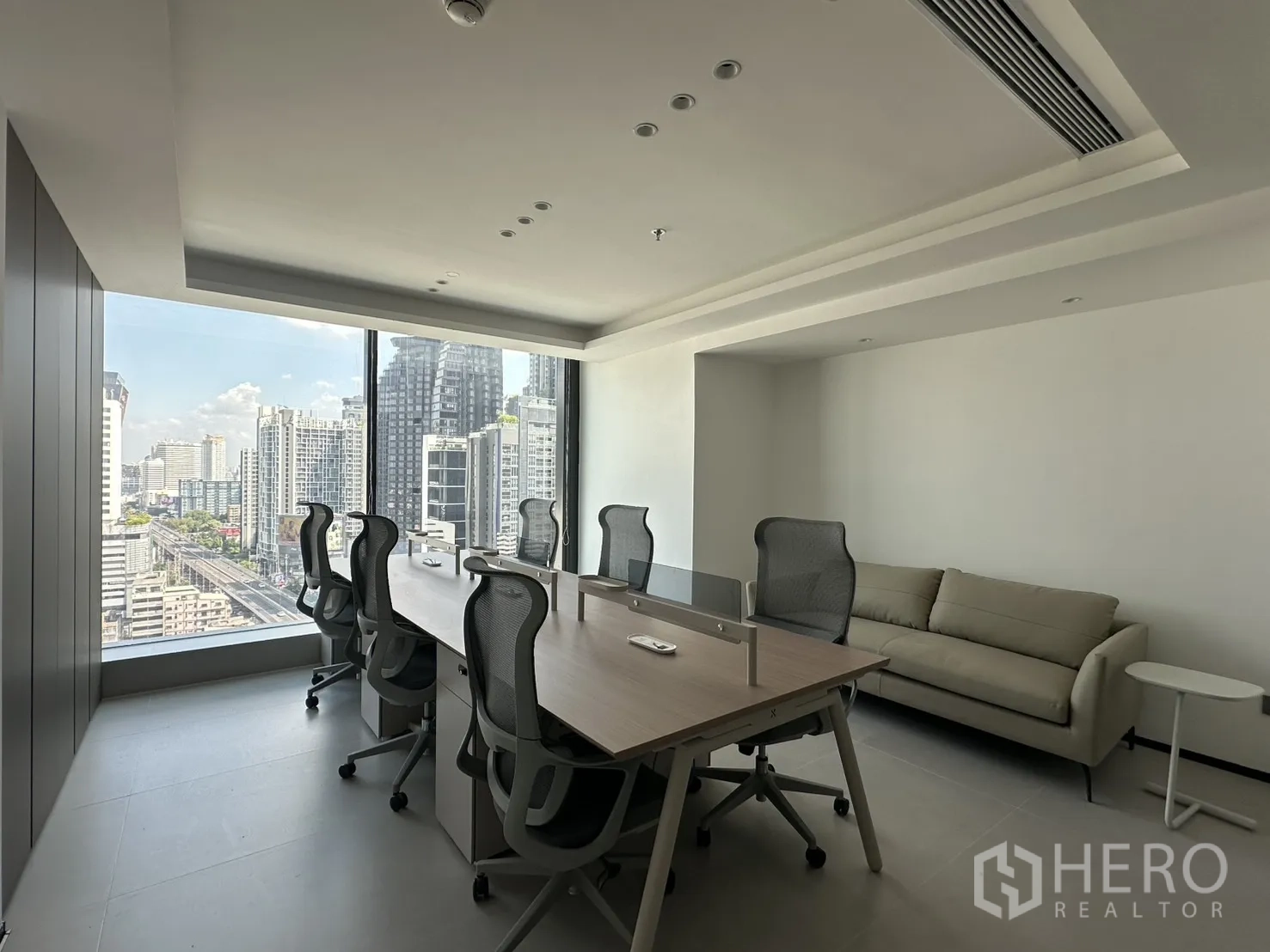 Office Space for rent in Din Daeng, Bangkok - Workroom with bench desks, mesh chairs, and a sofa by the window.