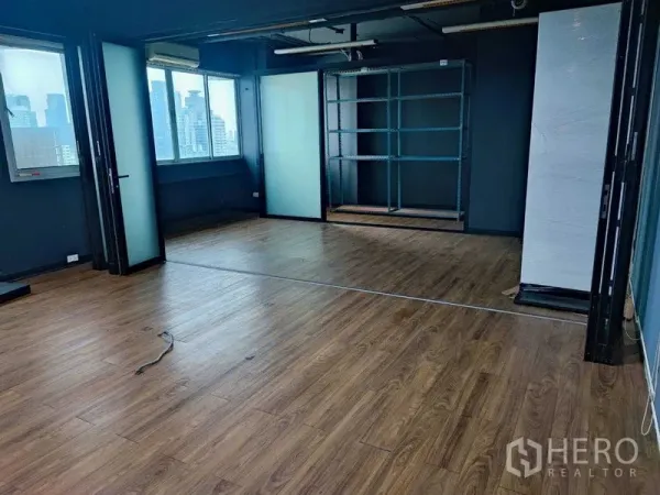 Office Space for rent in Watthana, Bangkok - Spacious office area with wood flooring, folding glass partitions, and a shelving niche.