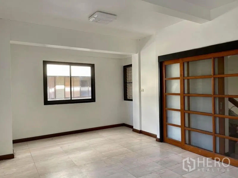 Home Office for rent in Khlong Toei, Bangkok - Open living or office area with tiled floor, window, and wooden sliding glass doors.