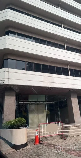Retail Space for rent - Facade of a modern commercial building with ground-floor retail entrance, steps and planters.