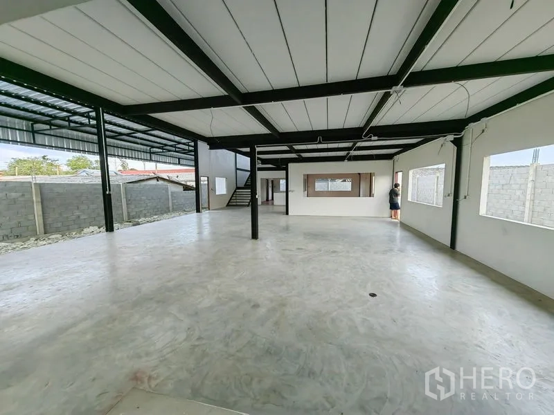 工厂 出租或出售在Mueang Samut Prakan, Samut Prakan - 首层工作区，钢柱支撑、大窗与通往夹层的楼梯。