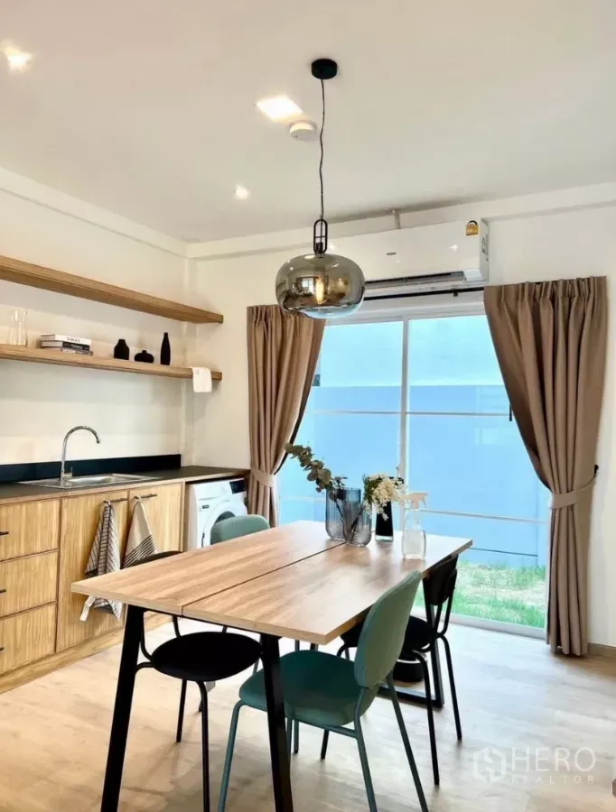 Townhouse for rent in Prawet, Bangkok - Bright dining kitchen with wood cabinets, pendant light, air conditioner and sliding glass door to the yard.