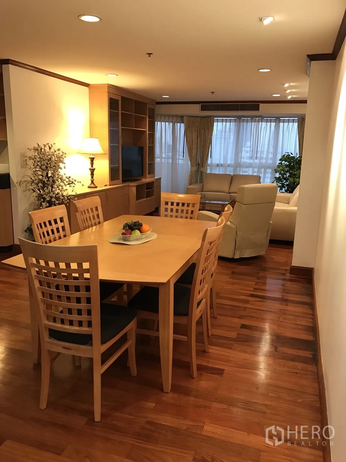 Condominium for rent in Khlong Toei, Bangkok - Open-plan dining area flowing to living room with built-in shelving and large windows.