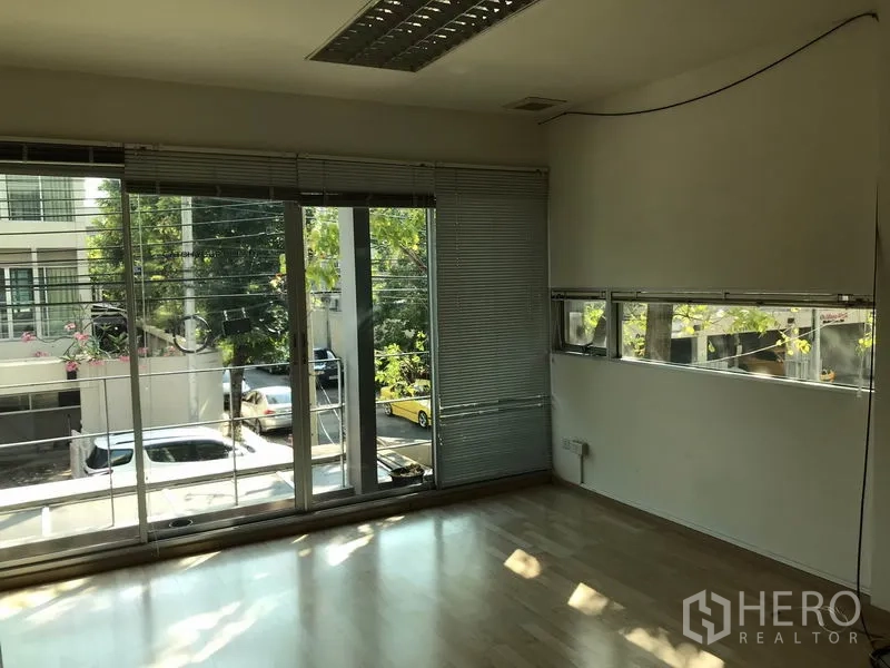 Townhouse for rent in Suan Luang, Bangkok - Second bedroom with balcony, blinds and street view through full-height windows.