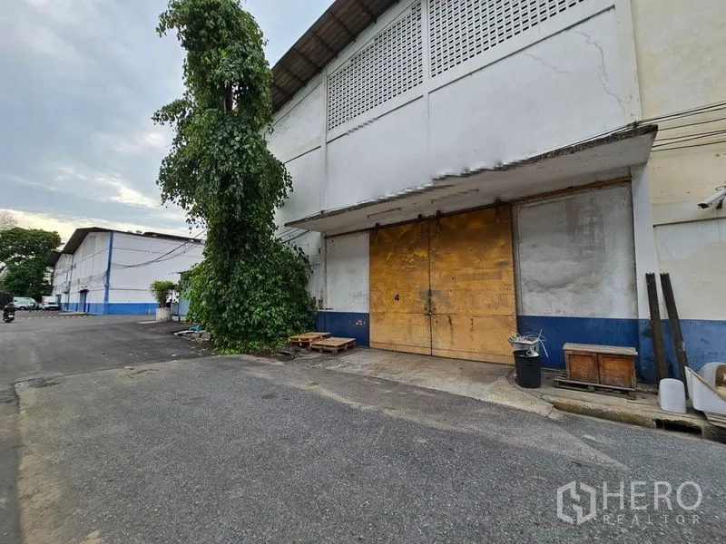 货栈 出租在Khlong Toei, Bangkok - 仓库外立面带大型滑动装卸门，前方车道宽敞可供卡车进出。