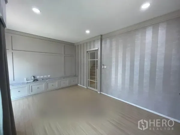 Townhouse for sale in Suan Luang, Bangkok - Second-floor family room with striped wallpaper, built-in TV console and recessed lighting.