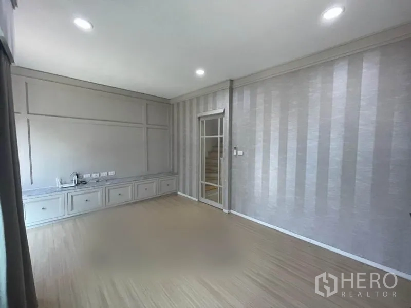 Townhouse for sale in Suan Luang, Bangkok - Second-floor family room with striped wallpaper, built-in TV console and recessed lighting.