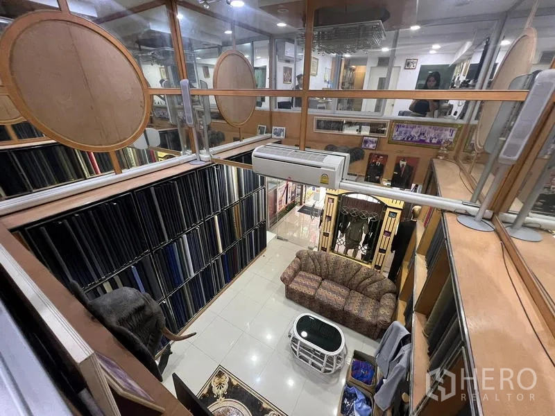 店屋 出租或出售在Watthana, Bangkok - 夹层俯瞰挑高展厅，可见展示墙与休息沙发。