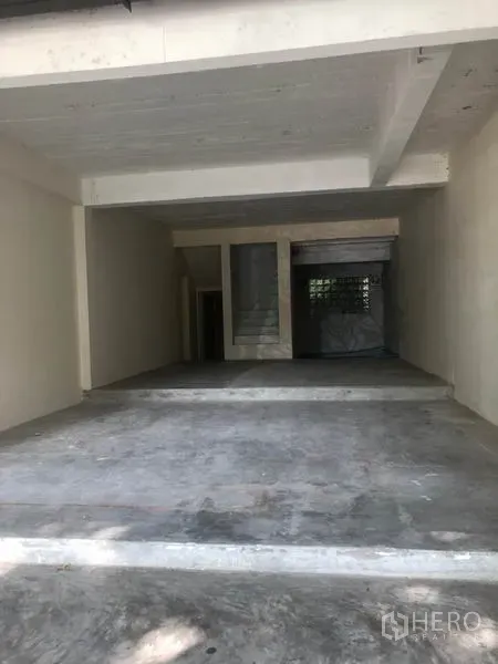 Retail Space for rent in Watthana, Bangkok - Open-plan interior shell with concrete floor, staircase and rear window.