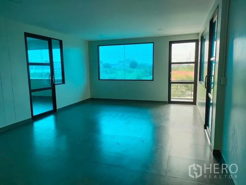 Factory for rent in Ban Phaeo, Samut Sakhon - Open-plan office with large picture window and side door to balcony.