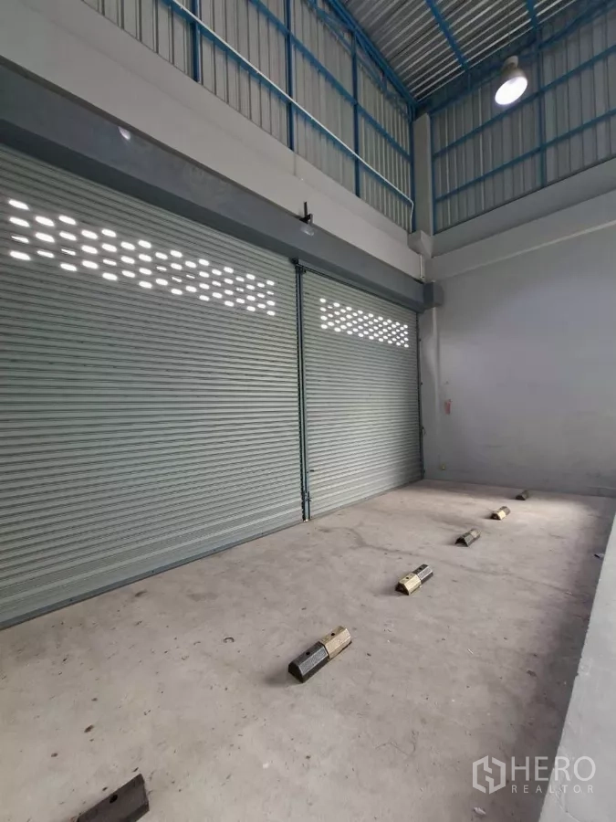 Warehouse for rent in Suan Luang, Bangkok - Ground-level loading zone with twin electric roller shutters and wheel stops.