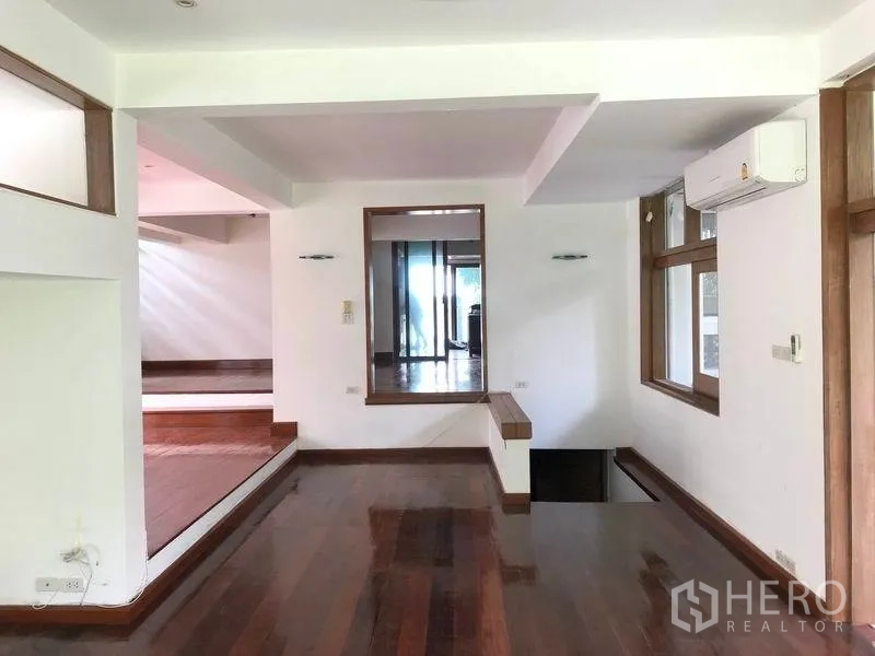 Detached House for rent in Watthana, Bangkok - Split-level living area with wooden floors and glass partitions.