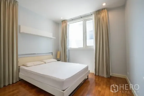 Condominium for rent or sale in Khlong Toei, Bangkok - Second bedroom with double bed, tall curtains and soft lighting.