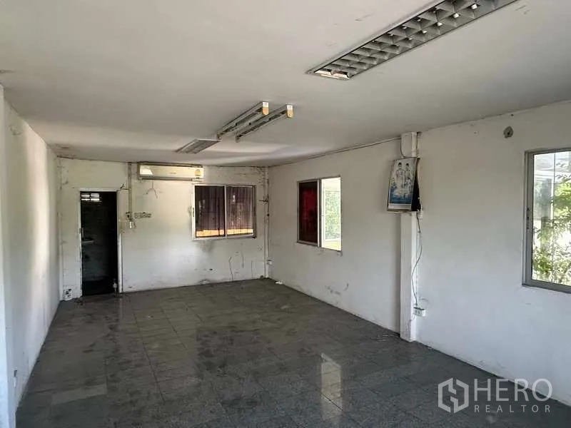 Warehouse for rent in Wang Noi, Phra Nakhon Si Ayutthaya - Empty office room with tiled floor, fluorescent lighting and multiple windows inside the warehouse compound.