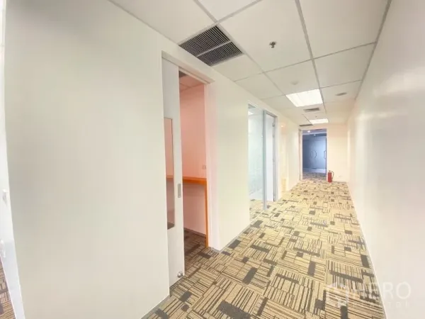 Office Space for rent in Chatuchak, Bangkok - Bright corridor with sliding door, carpet tiles, and glass-partitioned rooms in a modern office.